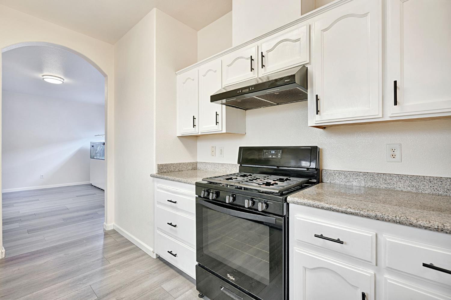 2061 Seventh Street Fresno, CA 93702 - Photo 7 of 38 a kitchen with white cabinets and a stove with wooden floors