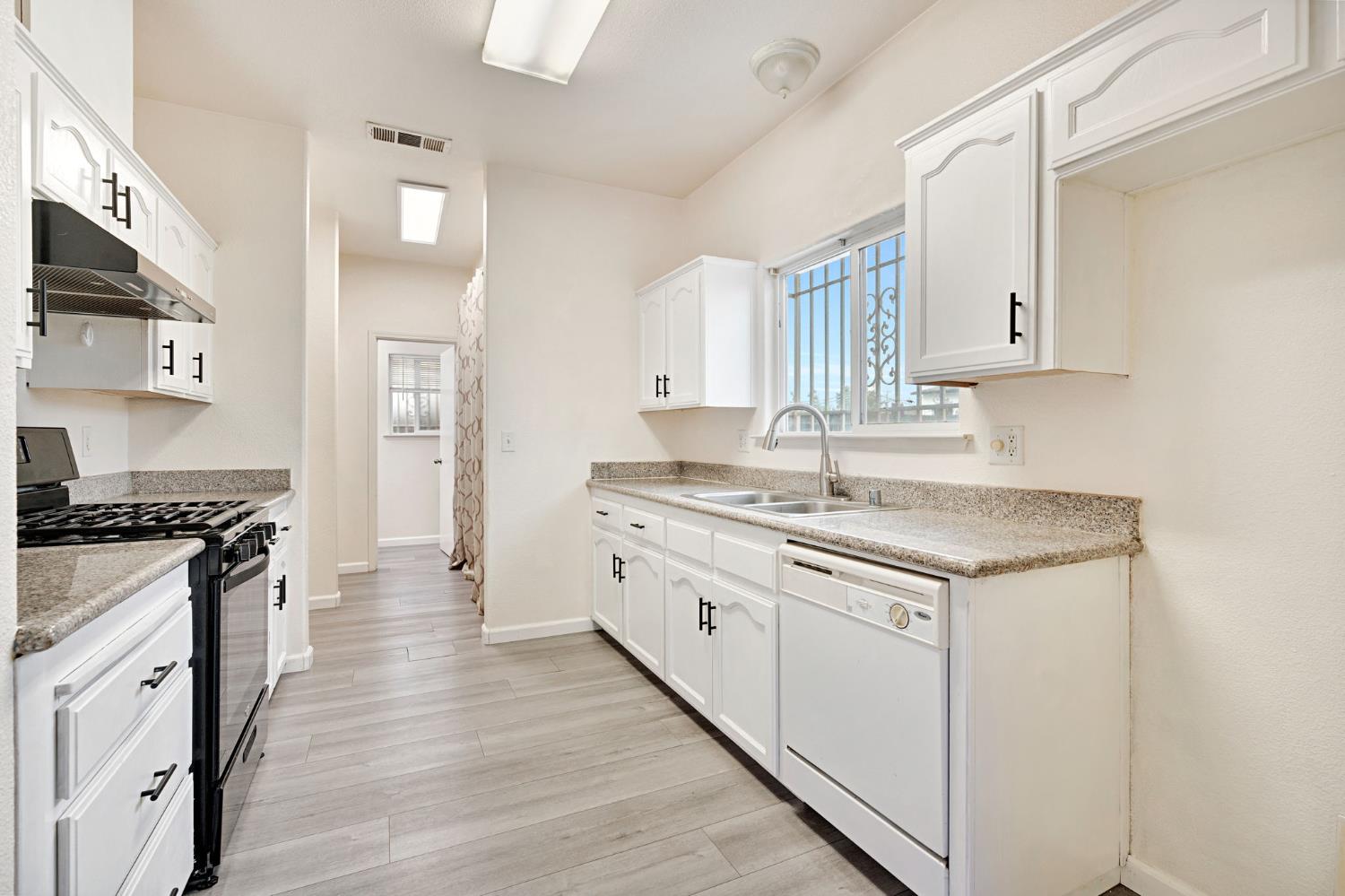 2061 Seventh Street Fresno, CA 93702 - Photo 10 of 38 a kitchen with granite countertop a sink stove and cabinets