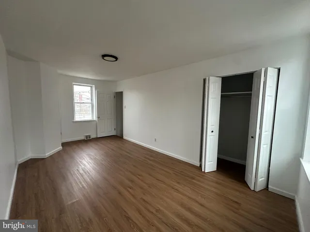 an empty room with wooden floor and window