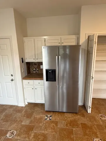 a view of a refrigerator in kitchen and white cabinets