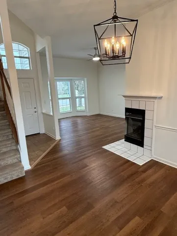 an empty room with wooden floor chandelier and fireplace