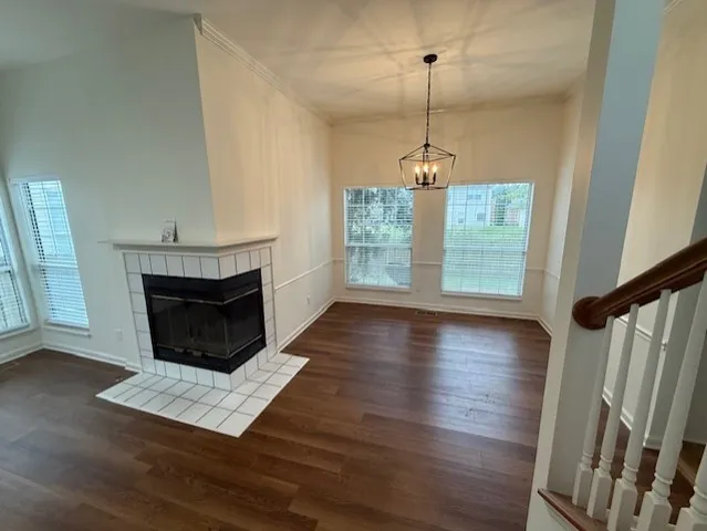a view of a room with wooden floor fireplace and window