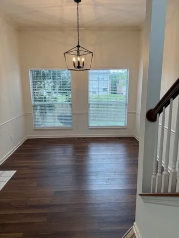 a view of a room with wooden floor chandelier and windows