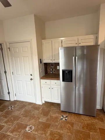 a view of a refrigerator in kitchen and white cabinets