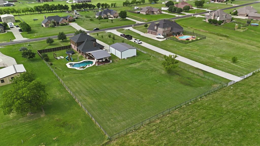 430 Ridgecrest Place Sanger, TX 76266 - Photo 38 of 40 Expansive property featuring a large brick residence with a dark shingle roof, a detached metal outbuilding, and a separate metal storage shed