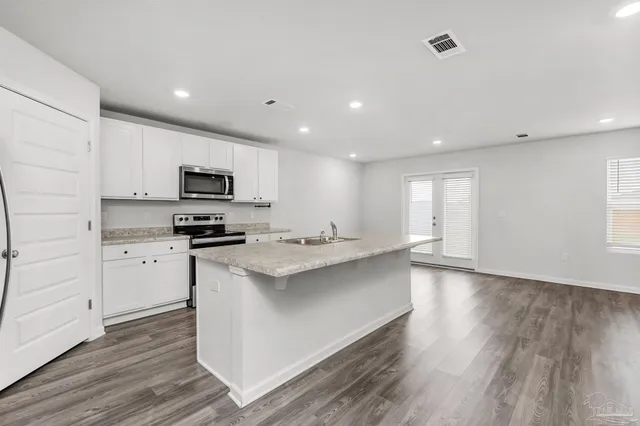 a kitchen with white cabinets appliances and sink