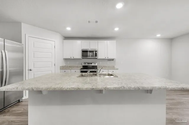 a kitchen with stainless steel appliances granite countertop a sink a stove and a refrigerator