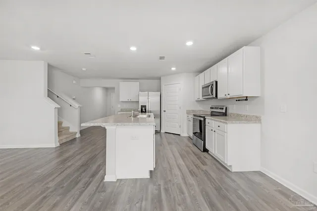 a large kitchen with cabinets wooden floor and stainless steel appliances