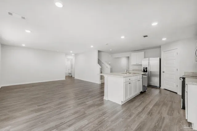 a kitchen with a sink wooden floor stainless steel appliances and cabinets