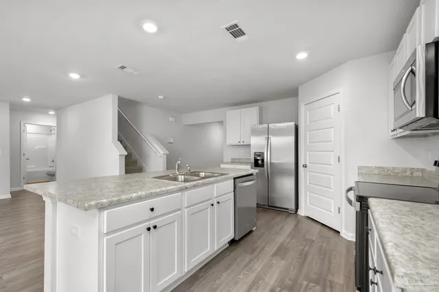 a large kitchen with stainless steel appliances granite countertop a lot of counter space and wooden floors