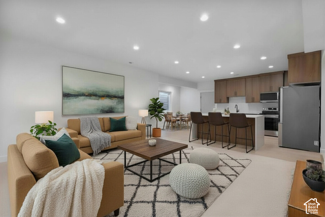 710 East Mountain Road Ogden, UT 84414 - Photo 9 of 10 Open-concept living space featuring recessed lighting, a kitchen island with seating, wood-finish cabinetry, stainless steel appliances, and light-toned flooring