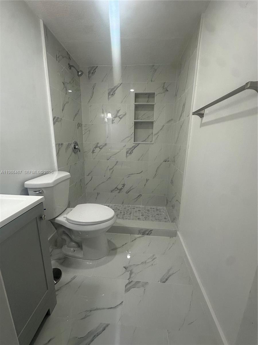2753 West 68th Place, Unit 1 Hialeah, FL 33016 - Photo 11 of 13 a white toilet sitting next to a bathroom sink and vanity