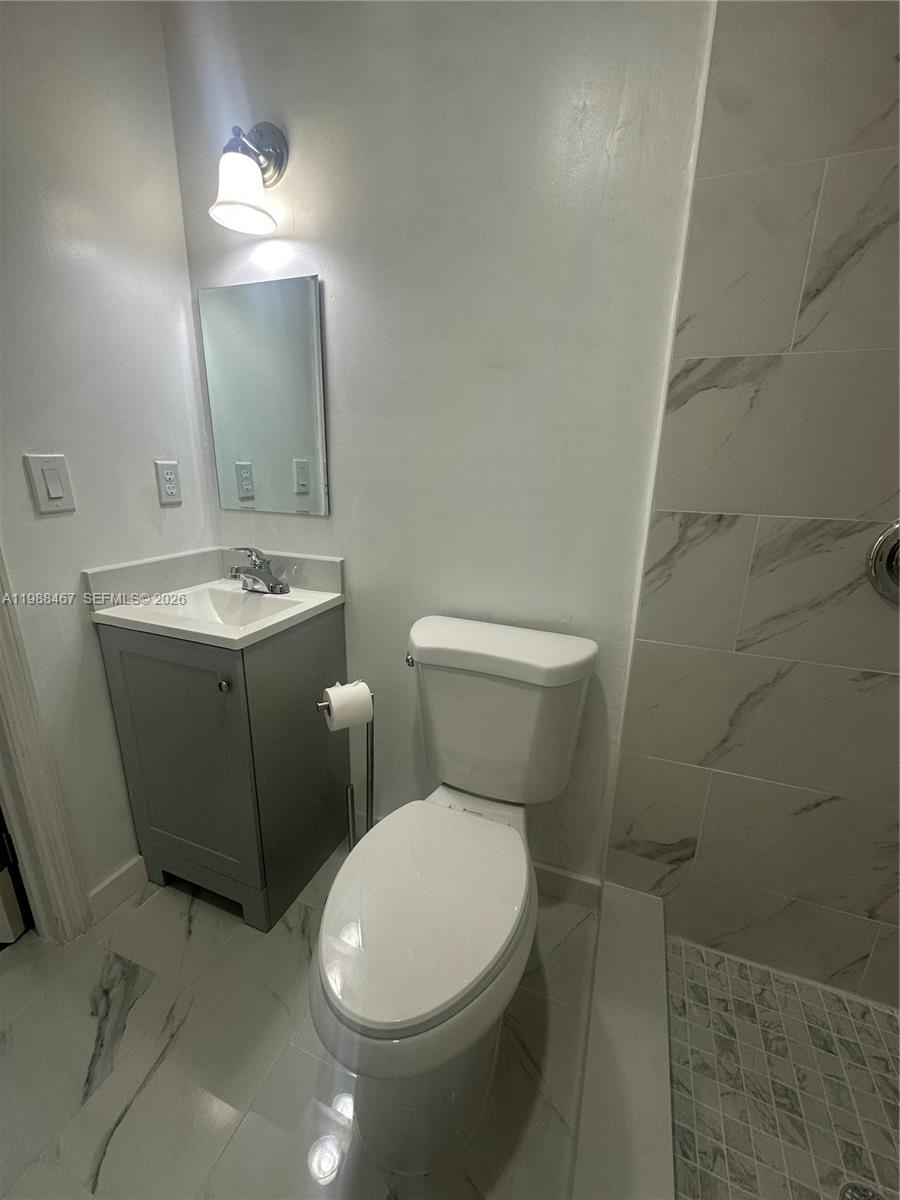 2753 West 68th Place, Unit 1 Hialeah, FL 33016 - Photo 13 of 13 a white toilet sitting next to a bathroom sink and vanity