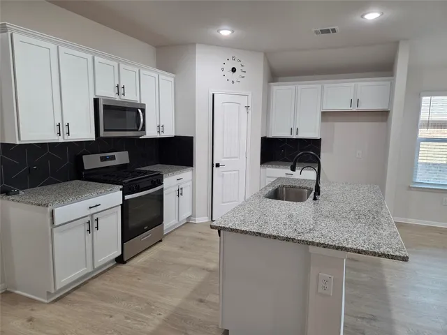 a kitchen with stainless steel appliances granite countertop a sink stove and refrigerator