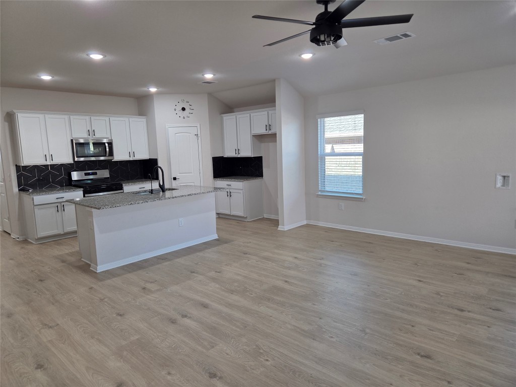 2421 Corriente Path Leander, TX 78641 - Photo 3 of 19 a living room with stainless steel appliances kitchen island granite countertop a stove a sink a refrigerator white cabinets and wooden floor