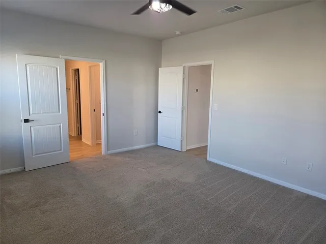 a view of an empty room and chandelier fan