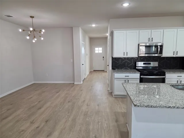 a large kitchen with stainless steel appliances a large counter top a stove a sink and dishwasher