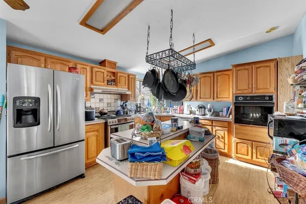 a kitchen with stainless steel appliances granite countertop a refrigerator a stove a sink dishwasher a dining table and chairs with wooden floor