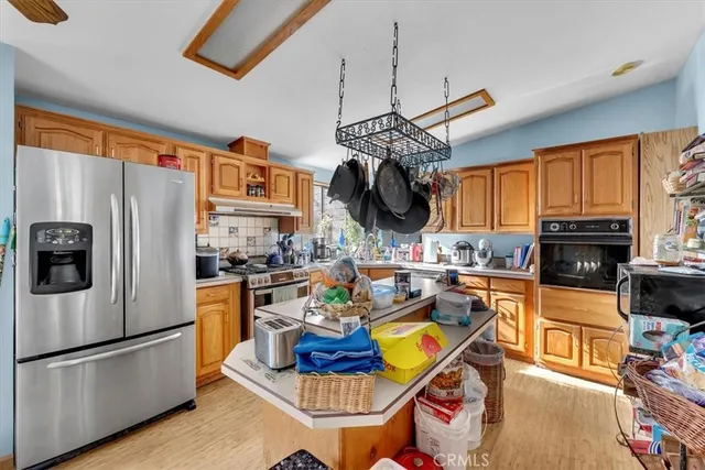 a kitchen with stainless steel appliances granite countertop a refrigerator a stove a sink dishwasher a dining table and chairs with wooden floor