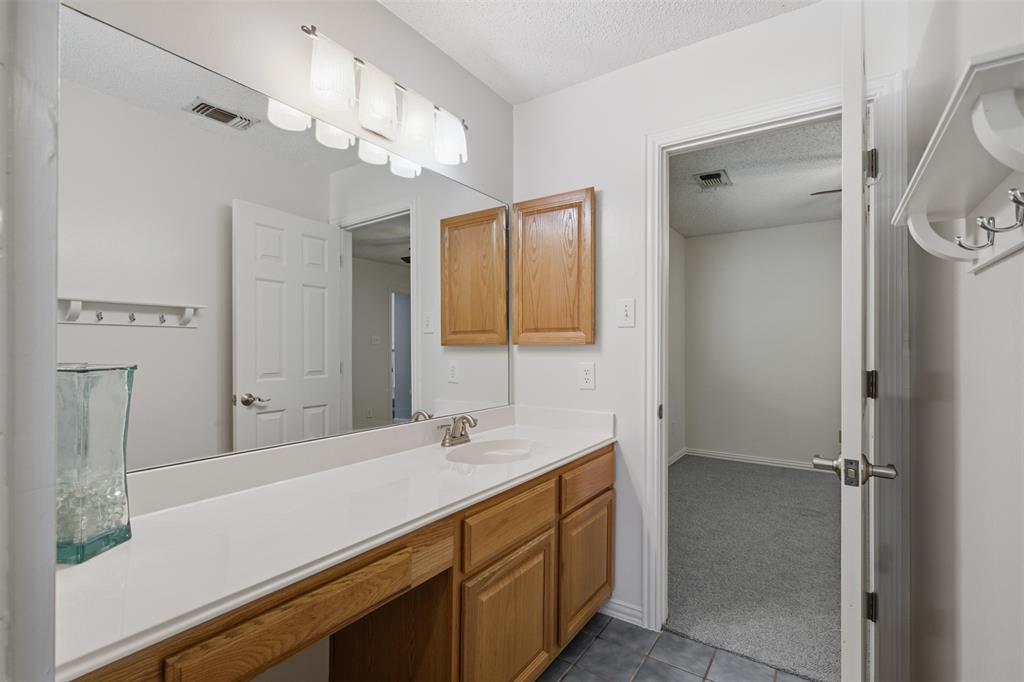 14584 Blueberry Court Addison, TX 75001 - Photo 29 of 40 a bathroom with a sink a mirror and a shower