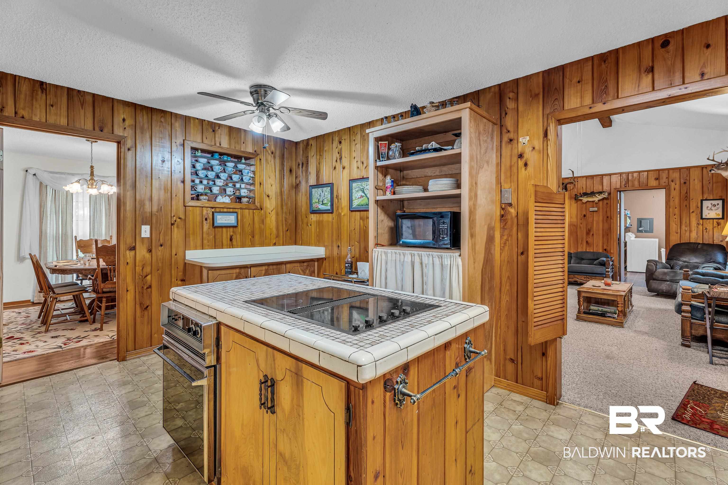 72075 Highway 59 Little River, AL 36550 - Photo 9 of 40 Kitchen with tile countertops, a ceiling fan, wood walls, light floors, and black appliances