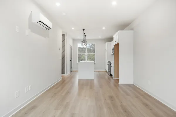a view of a hallway with wooden floor and a refrigerator