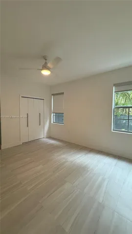 an empty room with windows and chandelier fan
