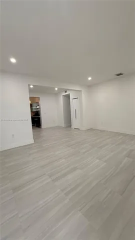 a view of a big room with wooden floor and windows