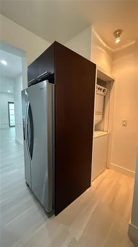 a view of a refrigerator in kitchen and an empty room