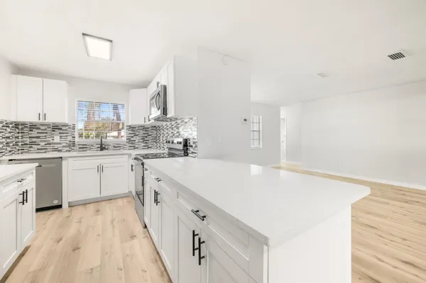 a kitchen with a sink a stove cabinets and a wooden floor