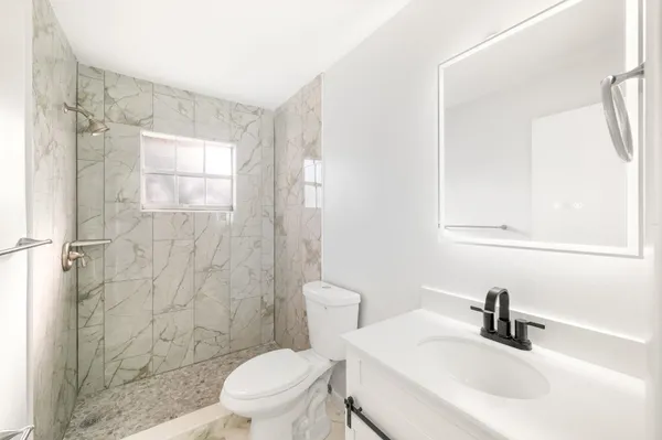 a bathroom with a sink a toilet and shower