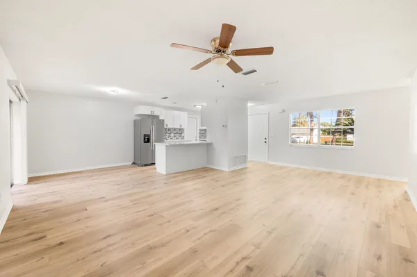 a view of empty room with wooden floor and ceiling fan