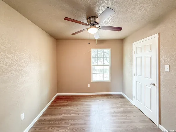 an empty room with wooden floor fan and windows