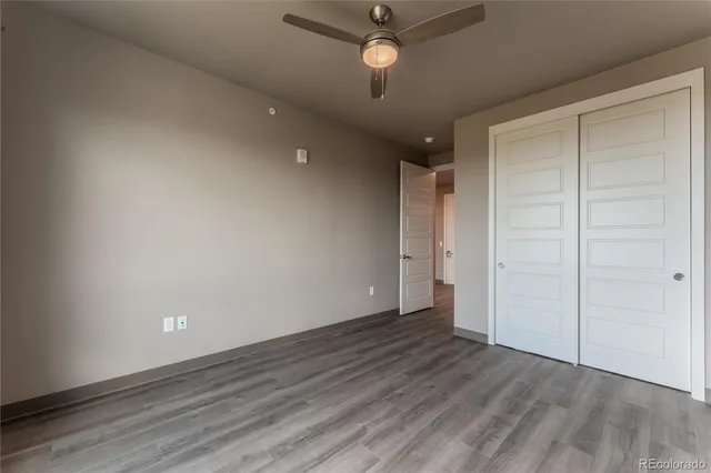 an empty room with wooden floor and a ceiling fan