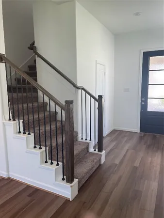 a view of a hallway with wooden floor and stairs