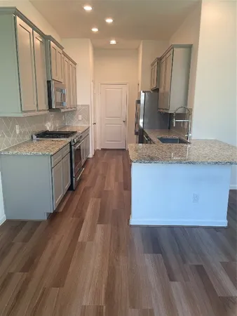 a large kitchen with wooden floors and stainless steel appliances
