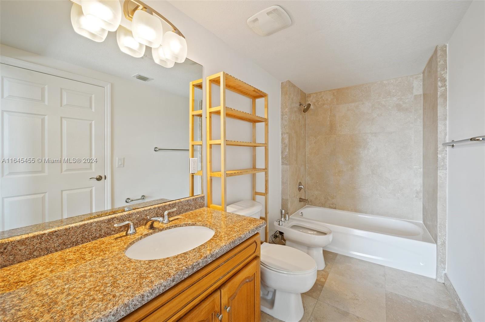 3530 Southwest 22nd Street, Unit 713 Miami, FL 33145 - Photo 31 of 41 a bathroom with a granite countertop sink a toilet a mirror and shower