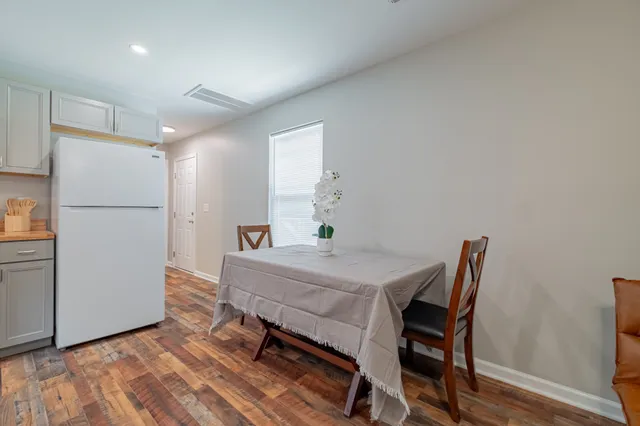 a living room with stainless steel appliances furniture a rug and a kitchen view