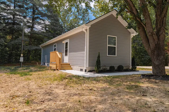 a view of a house with backyard and trees