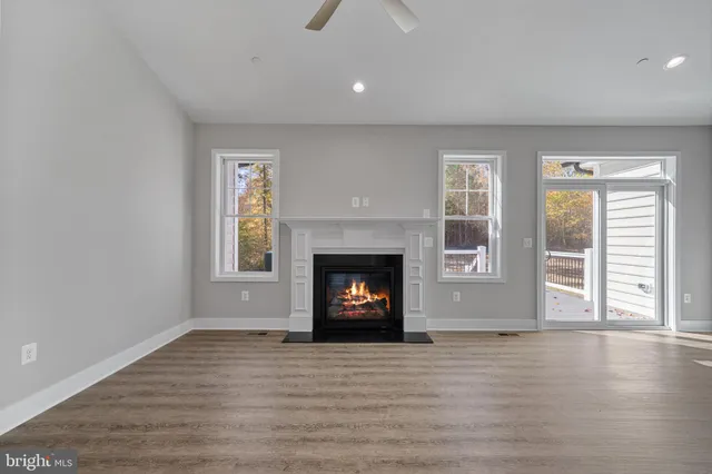 a view of an empty room with wooden floor fireplace and a window