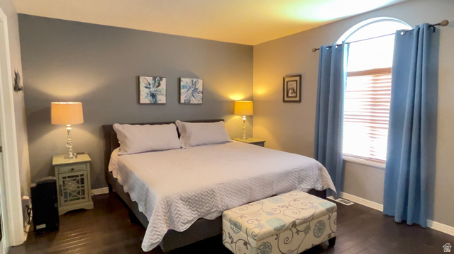 1797 Sunset Road Enoch, UT 84721 - Photo 21 of 80 Bedroom featuring wood-finish flooring, a wall with contrasting paint, and an arched window with blinds