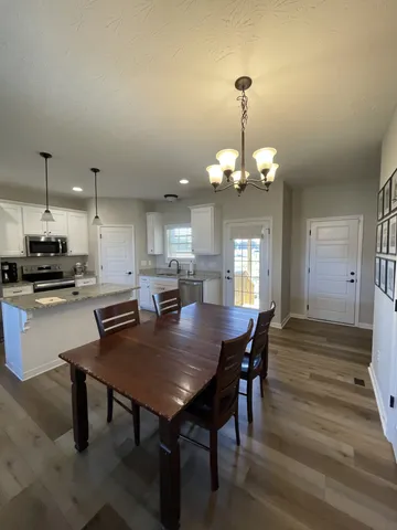 a dining room with wooden floor a chandelier a wooden table and chairs