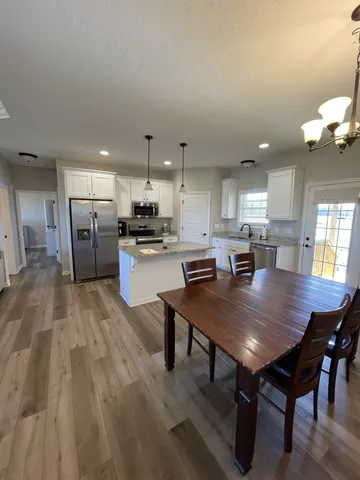 a kitchen with a dining table chairs and refrigerator