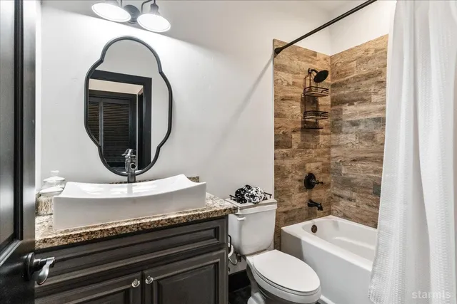 a bathroom with a granite countertop toilet sink and mirror