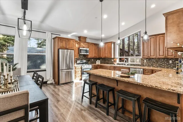 a kitchen with granite countertop a table chairs stainless steel appliances and wooden floor