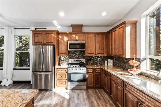a kitchen with kitchen island granite countertop a refrigerator stove top oven and sink