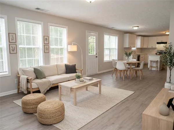 an empty room with wooden floor and a kitchen