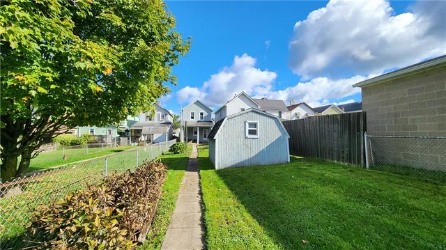 a view of a back yard with flower plants and wooden fence