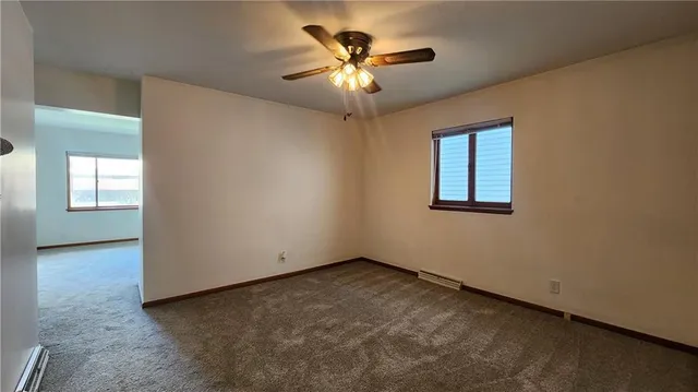 an empty room with windows and ceiling fan