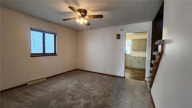an empty room with chandelier fan and windows